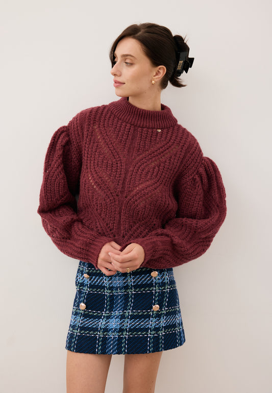 Modelka w bordowym ażurowym swetrze ROSSO i granatowej spódniczce w kratę DISSA.