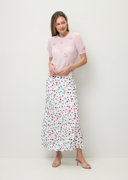 Modelka ubrana w spódniczkę midi MOLLENA w print w poziomki oraz sweterek z krótkim rękawem i ozdobnymi różami ADRIS.