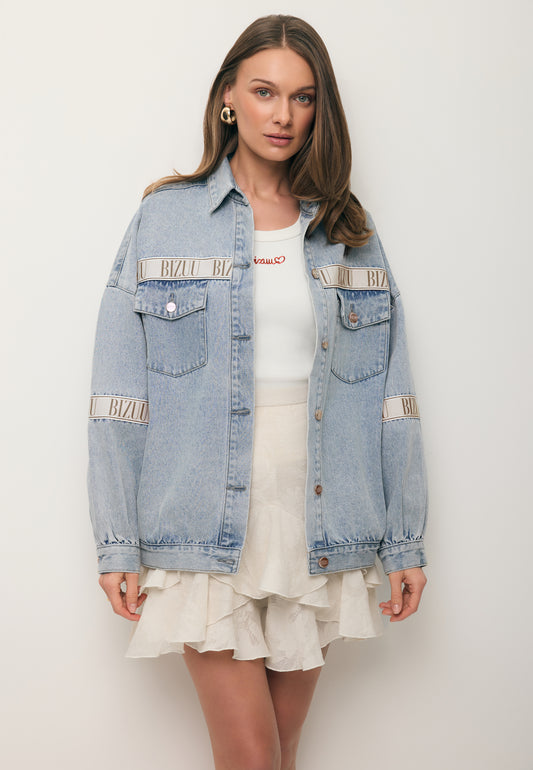 Modelka ubrana w błękitną kurtkę jeansową z logowaną taśmą PASSA oraz spódniczkę w kwiatowy wzór ANAIS.