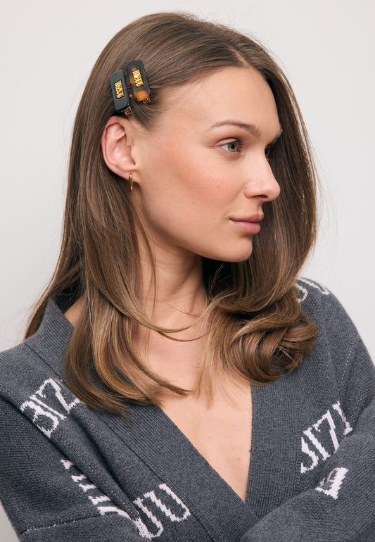 Zbliżenie na modelkę z włosami upiętymi małymi spinkami CATTA w kolorze czarnym i brązowym.