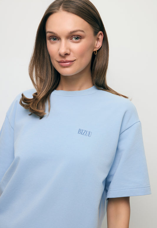 Zbliżenie na modelkę ubraną w błękitny T-shirt z małym logo na przodzie CLOUD.
