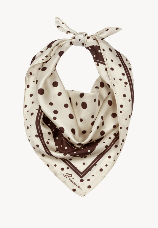 Beżowa jedwabna apaszka FIORIA złożona w trójkąt i związana pokazując ułożenie na szyi.