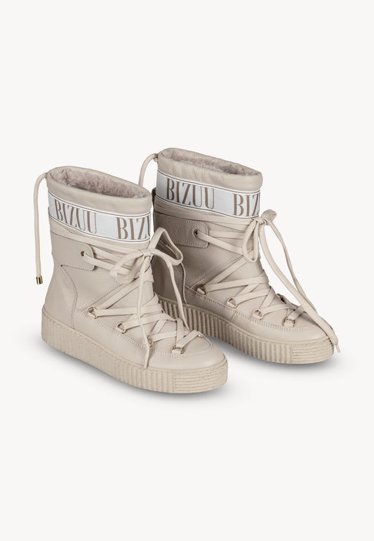 Beżowe śniegowce ESPEN z ozdobnym logo i sznurowaniem stojące pod kątem.