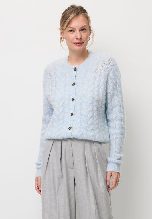 Modelka ubrana w błękitny kardigan ze złotymi guzikami EZELLA oraz szare spodnie z prostą nogawką BANOS.