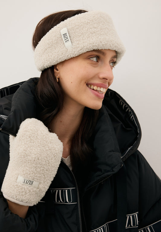 Uśmiechnięta modelka w kremowej opasce z kożuszka FUZZKA oraz rękawiczkach z tego samego materiału SNUGGIE.