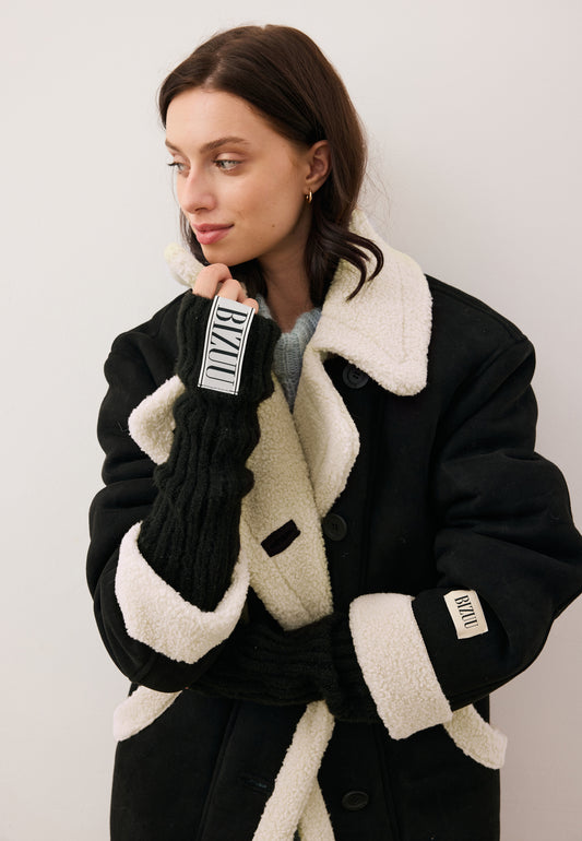 Modelka z ręką przy twarzy w czarnej mitence GINGI z logo BIZUU.