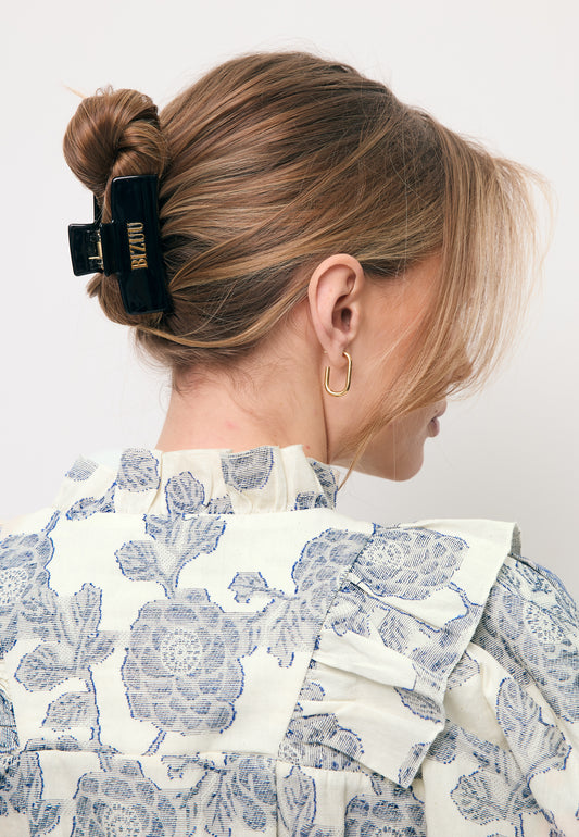 Zbliżenie na włosy modelki z czarna logowaną klamrą GLIMMA.