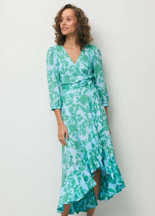 Modelka ubrana w niebieską sukienkę z ozdobną falbaną HUELVA.