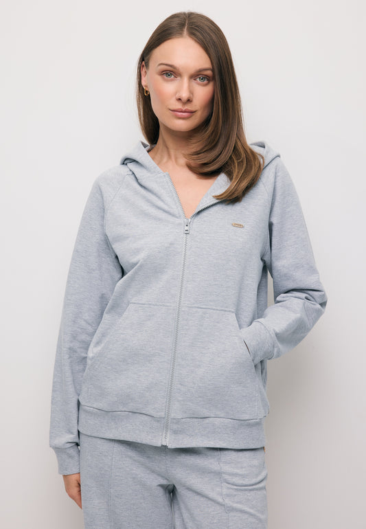 Zbliżenie na modelkę z ręką w kieszeni rozpinanej, szarej bluzy z kapturem IANELLA.