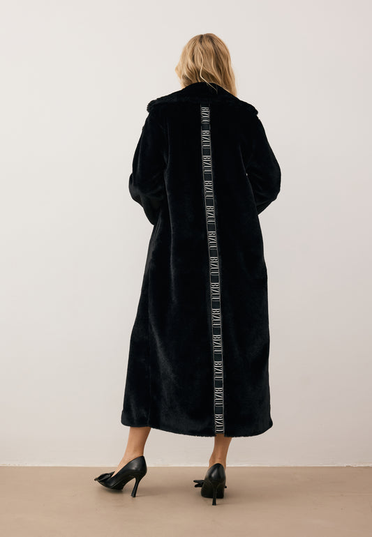 Modelka stojąca tyłem w długim futrzanym płaszczu LIVORNO z lampasem na plecach.