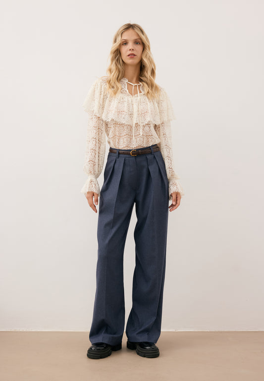 Modelka ubrana w koronkową koszulę MARLY oraz granatowe spodnie BANOS z szerokimi nogawkami.