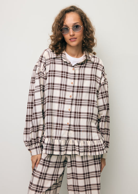 Modelka ubrana w koszulę w kratę i ozdobną falbaną FALBI.