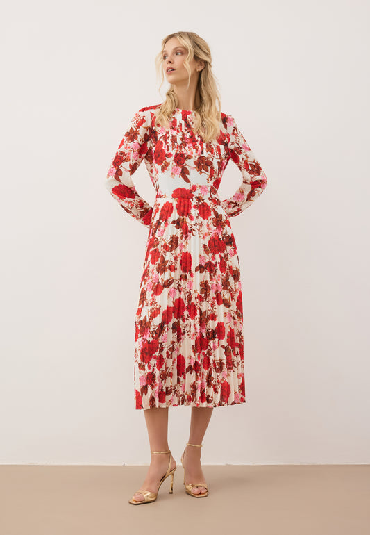 Modelka ubrana w midi sukienkę NYLA w kwiatowy print, sukienka z długim rękawem i plisowanym dołem.