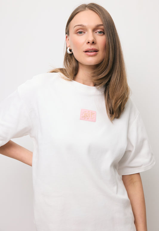 Zbliżenie na modelkę w białym T-shircie z logo na przodzie PARADISO.