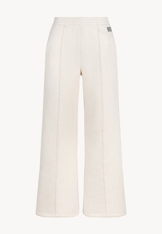 Przód luźnych spodni dresowych PETRA z przeszyciami i logo na kieszeni.