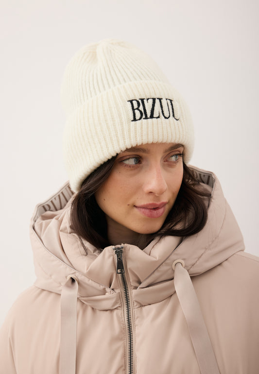 Zbliżenie na modelkę w kremowe czapce merino z czarnym haftem z logo ROYU.