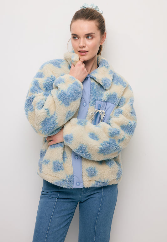 Modelka na tle białej ściany ubrana w kurtkę polarową z wełną TEDDY w kolorze niebiesko-kremowym.