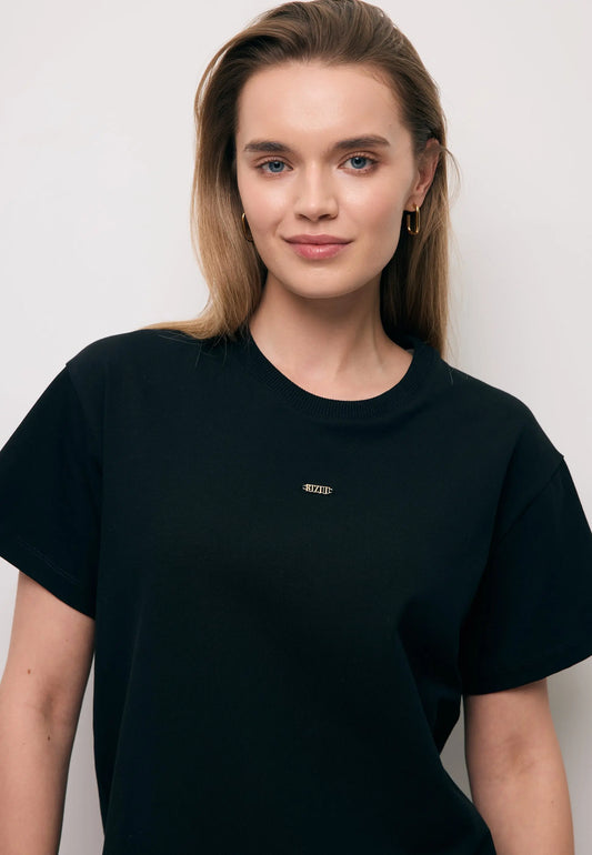 Zbliżenie na modelkę w czarnym T-shircie TISHAL z logo na przodzie.