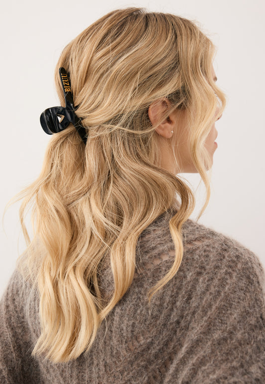 Zbliżenie na włosy modelki upięte czarna klamrą WILDA ze złotym logo Bizuu.
