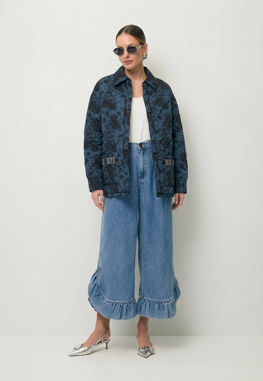 Modelka ubrana w granatową kurtkę w print MARIN oraz spodnie z ozdobną falbaną NELLY.