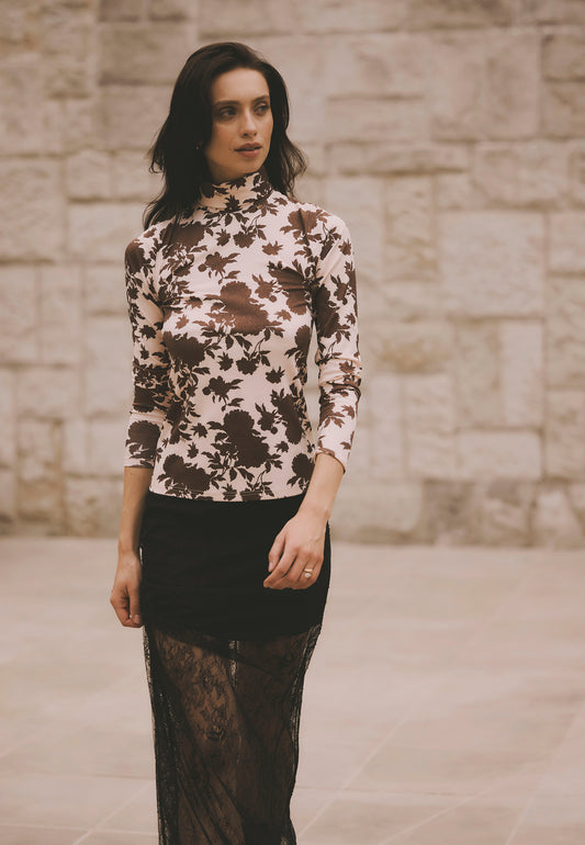 Modelka idąca ulicą ubrana w beżowy golf OWAKA w brązowe kwiaty i koronkową spódnicę FLACE.