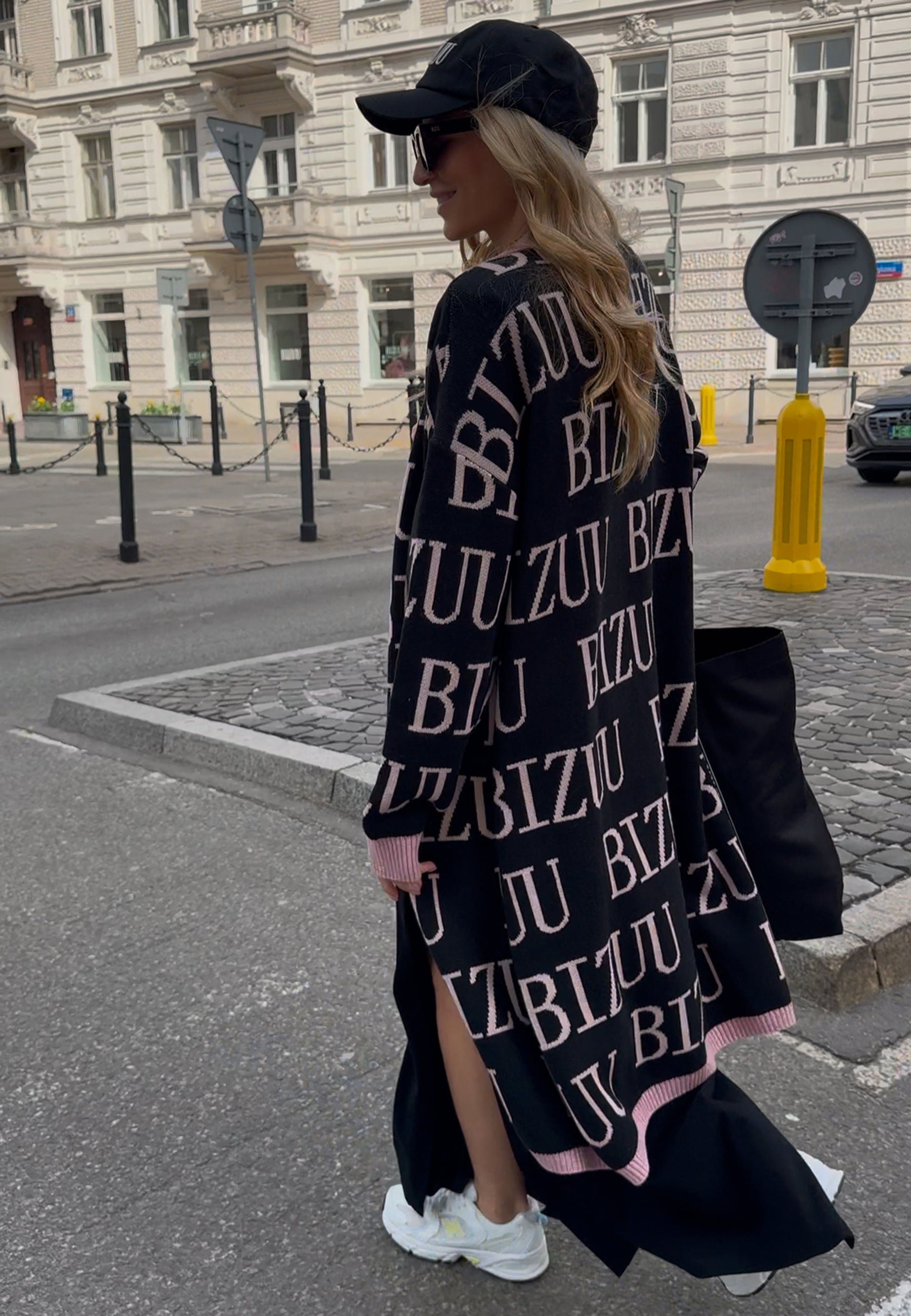 Modelka na ulicy ubrana w czarny kardigan w logo CHIOS.