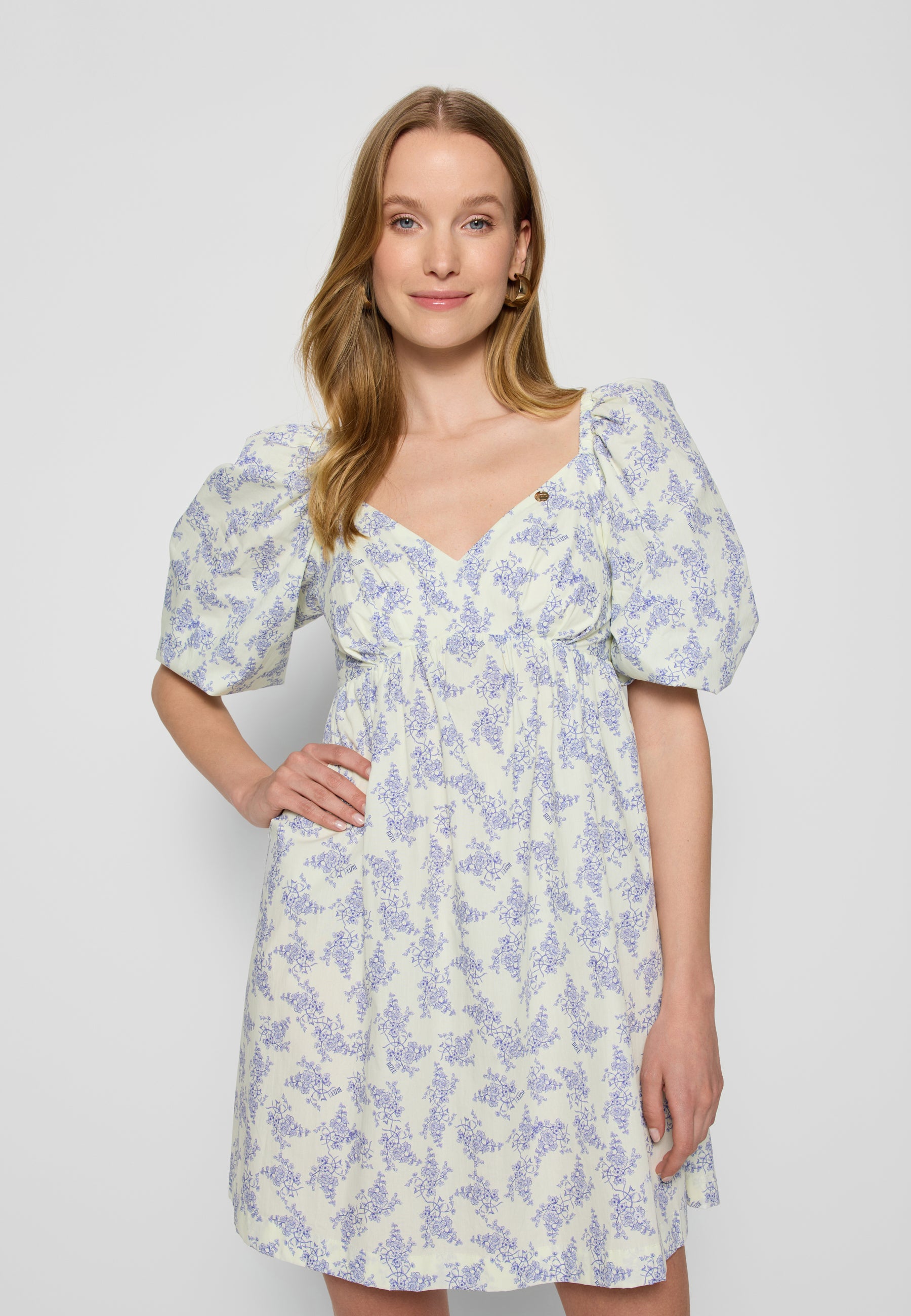 Zbliżenie na modelkę na białym tle ubranej w mini sukienkę ALMAR.