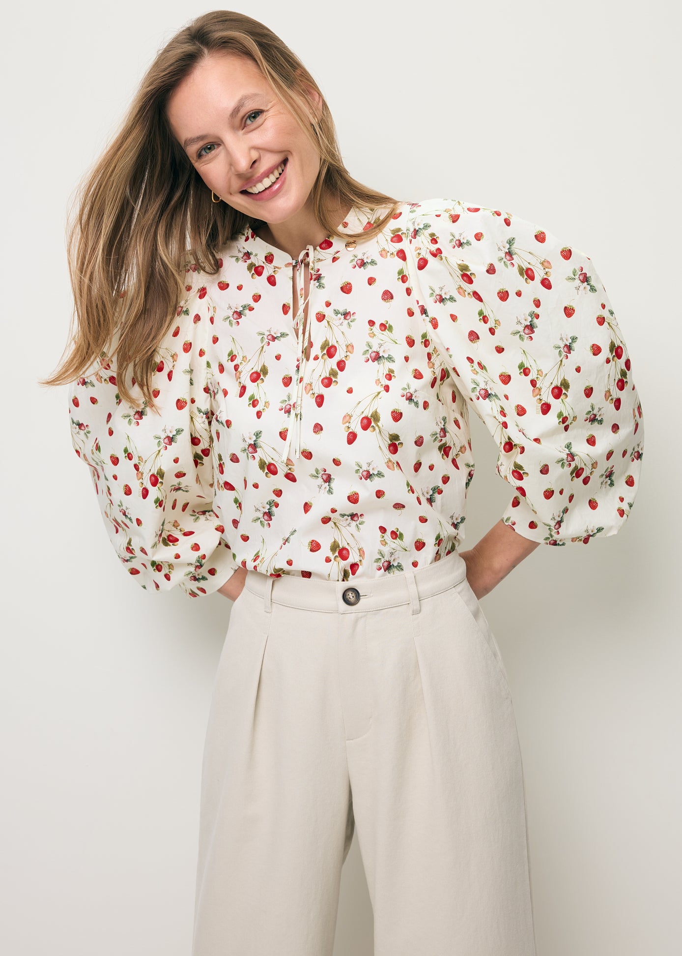 Zbliżenie na uśmiechniętą modelkę ubraną w bluzkę z bufiastymi rękawami w print poziomek ANDRASSA.