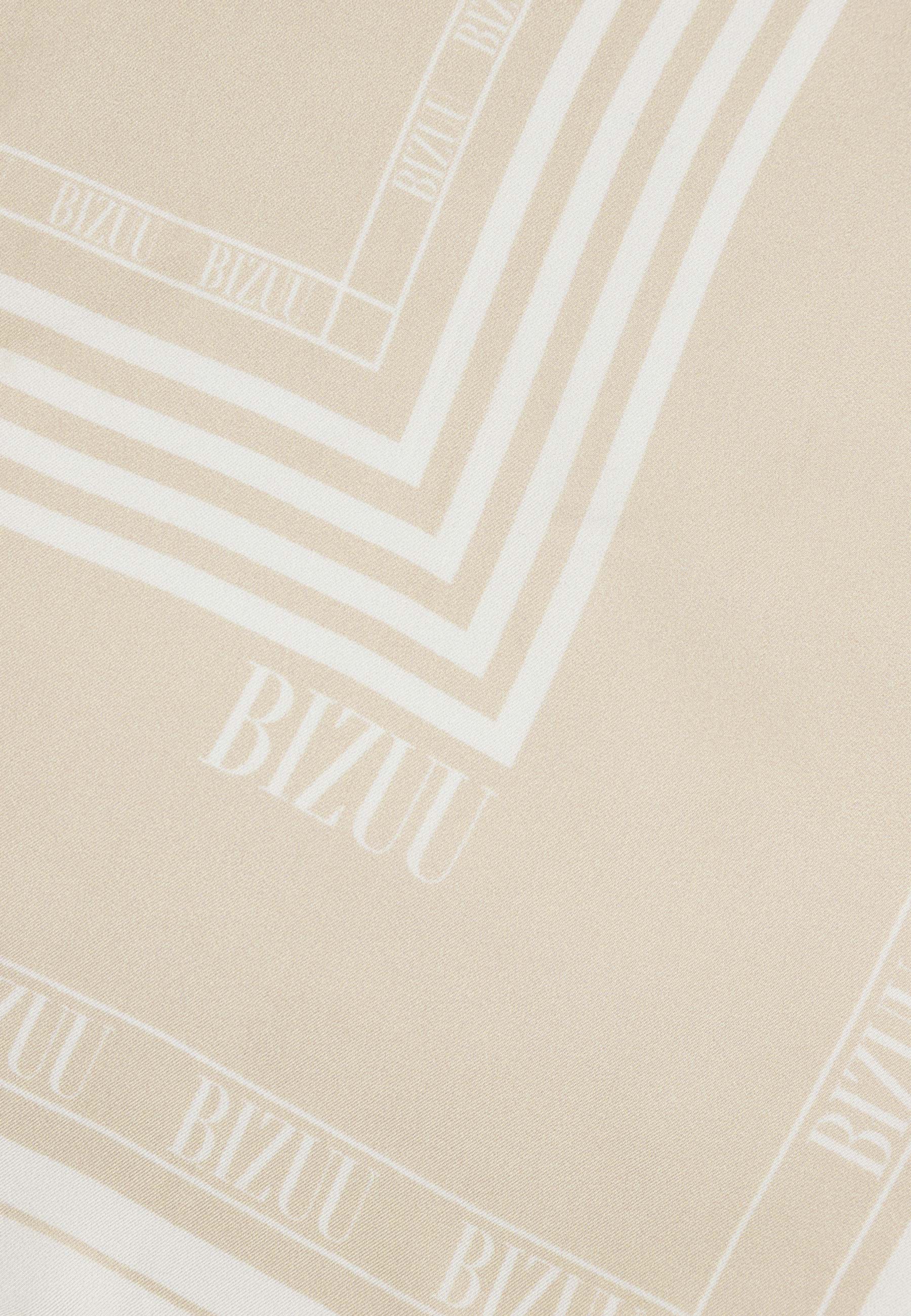 Zbliżenie na logo na beżowej, jedwabnej apaszce ARIA.