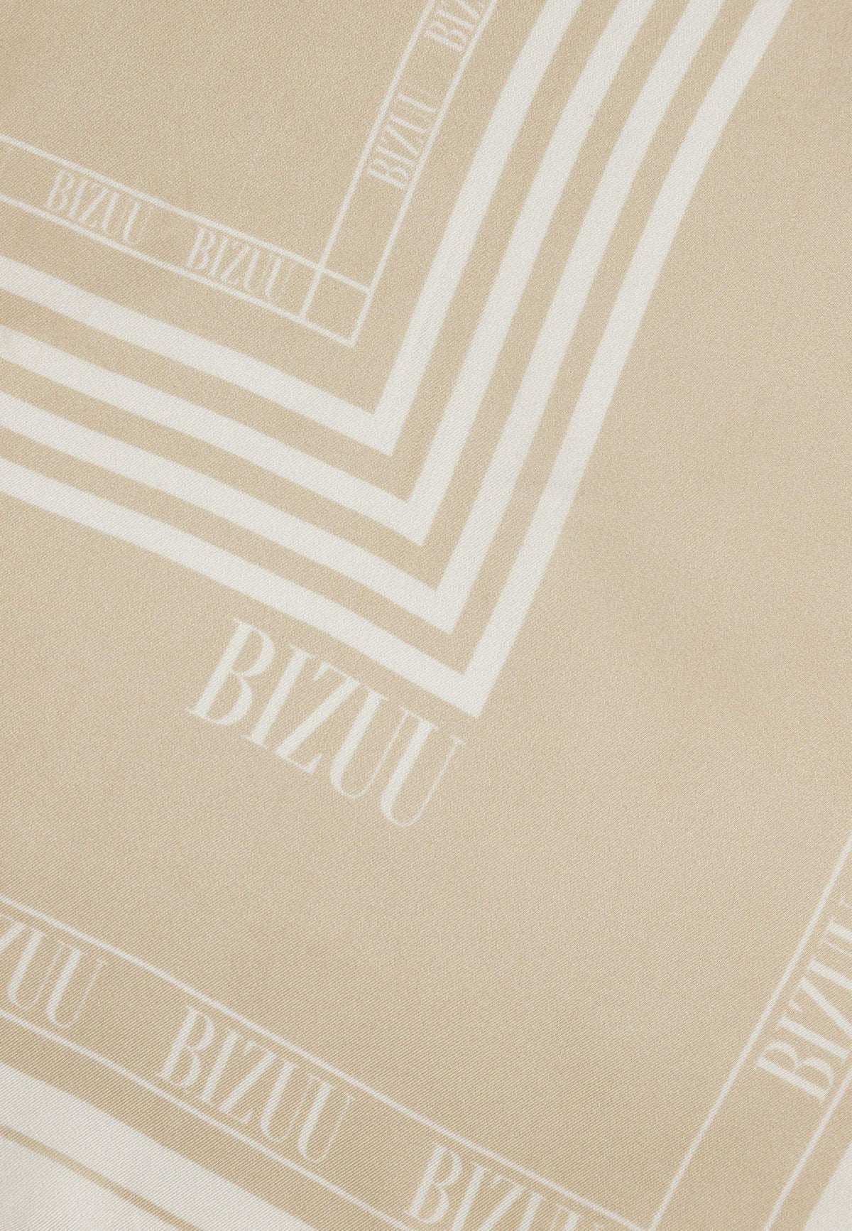 Zbliżenie na logo na beżowej, jedwabnej apaszce ARIA.
