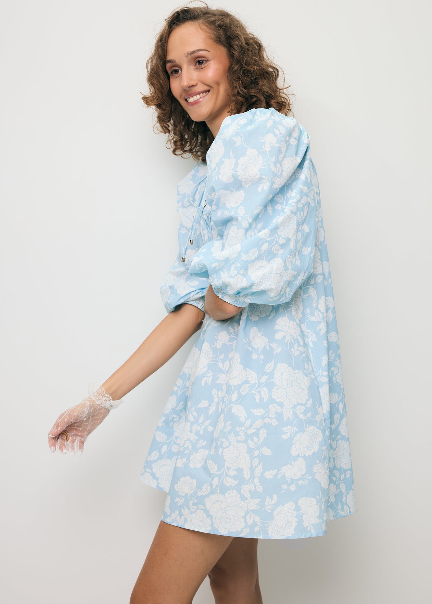 Modelka stojąca bokiem prezentująca bufiasty rękaw w mini sukience AYOTE.