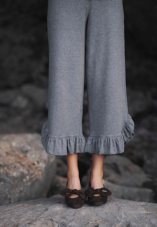 Zbliżenie na nogi modelki w szarych dresowych spodniach z ozdobną falbaną BAYLE.