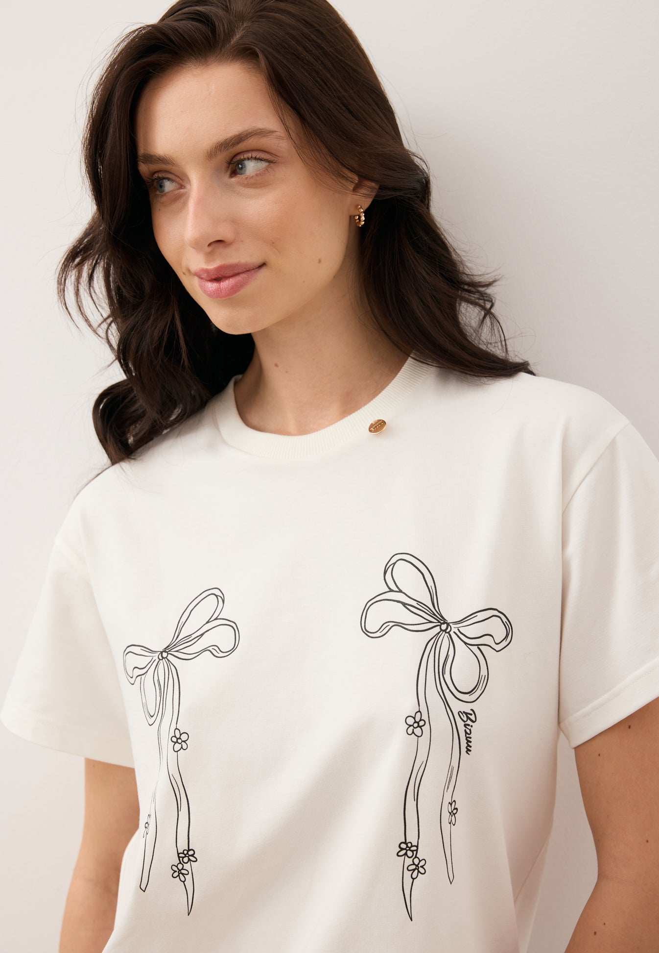 Zbliżenie na modelkę ubraną w T-shirt z rysunkiem kokardek BOW.