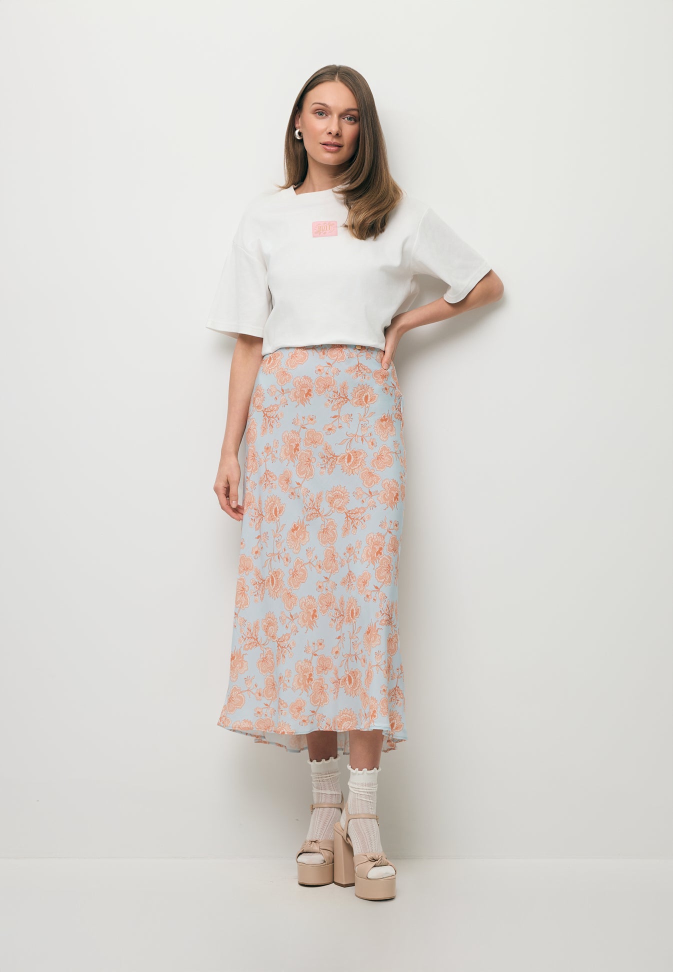 Modelka ubrana w biały T-shirt PARADISO oraz wiskozową spódnicę midi BREE.