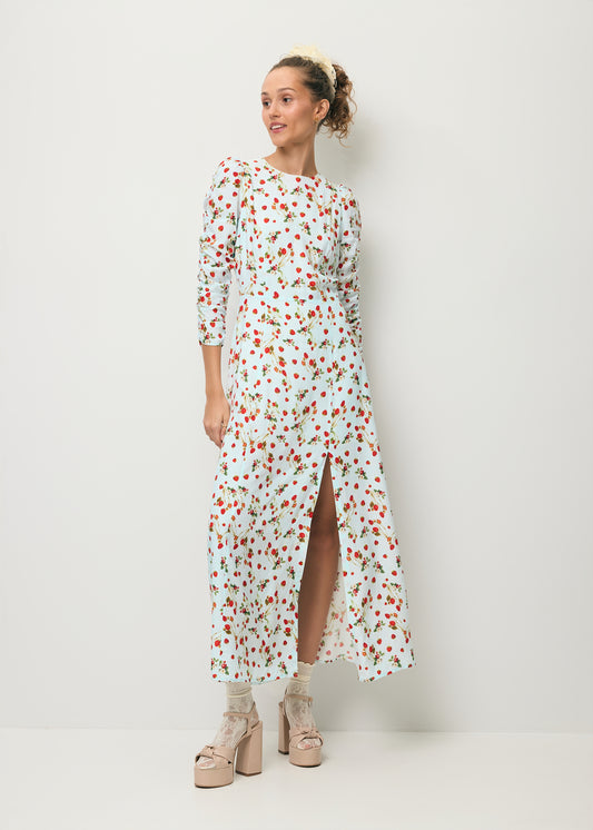 Modelka ubrana w sukienkę midi w print z poziomkami CALANA oraz z rozcięciem na nogę.