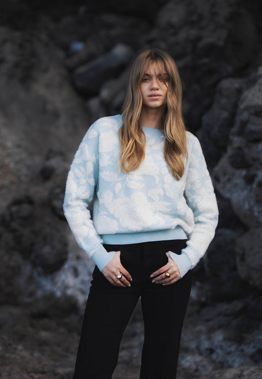 Modelka z założonymi rękoma w błękitnym swetrze w kwiatowy wzór CANELLO.