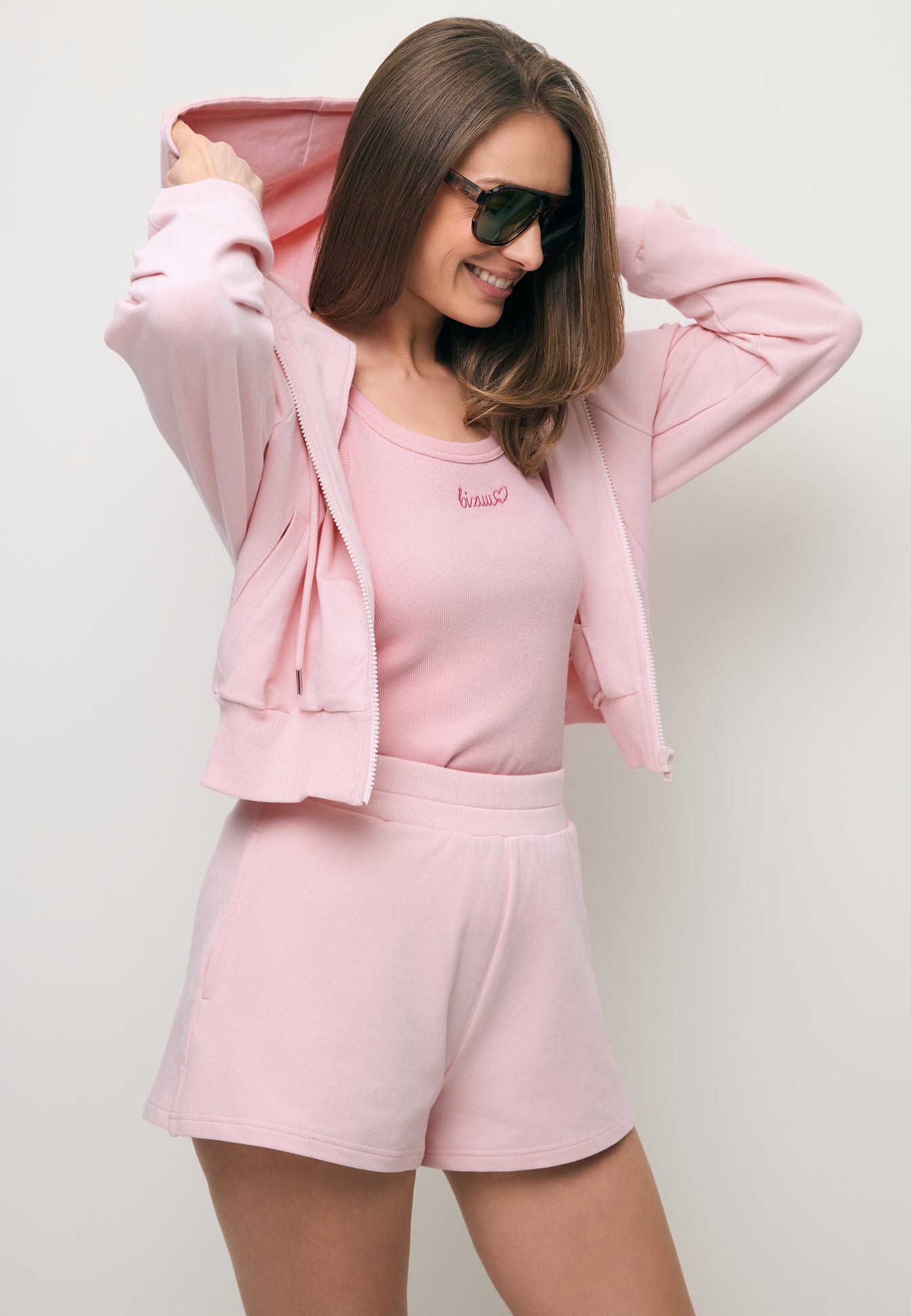 Modelka ubrana w różowy komplet dresowy CIANA i ETHIES oraz różowy prążkowany top LOVIE.