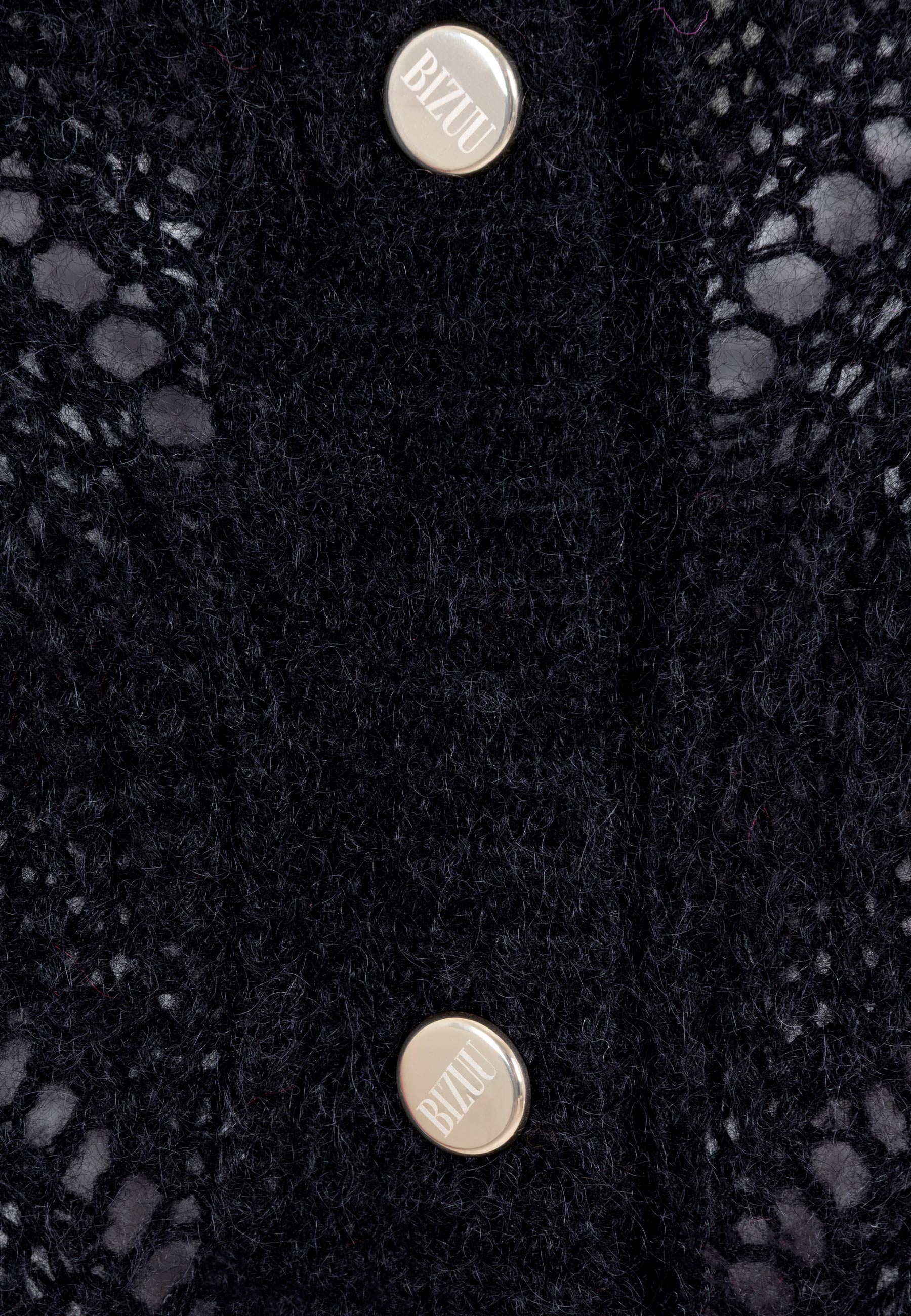 Zbliżenie na logowane guziki przy swetrze CLARA w kolorze czarnym.