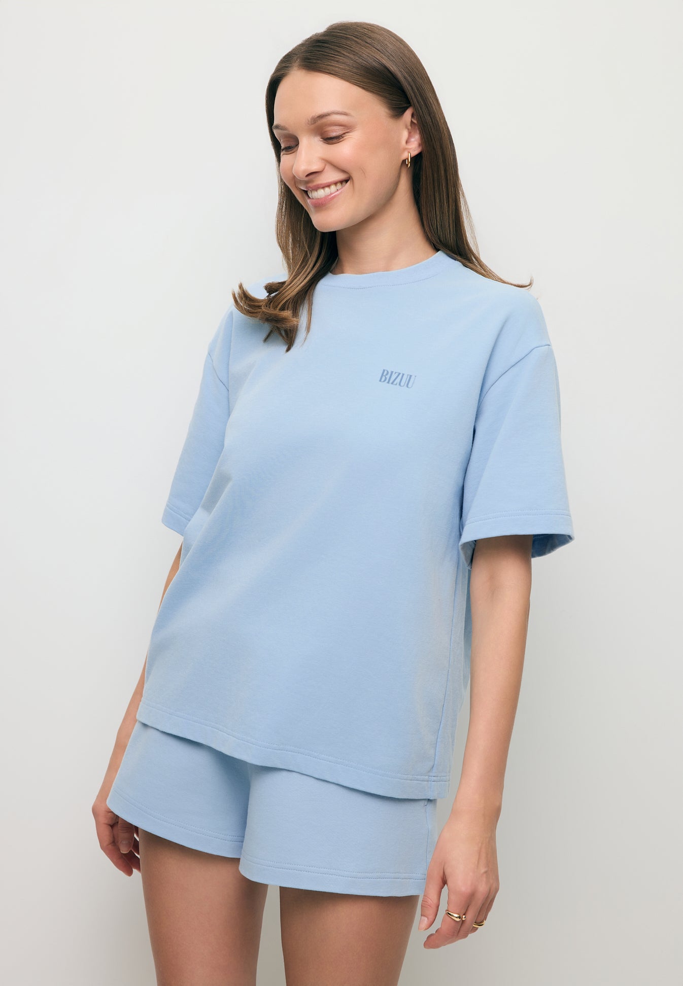 Uśmiechnięta modelka ubrana w oversizowy T-shirt w kolorze błękitnym CLOUD.