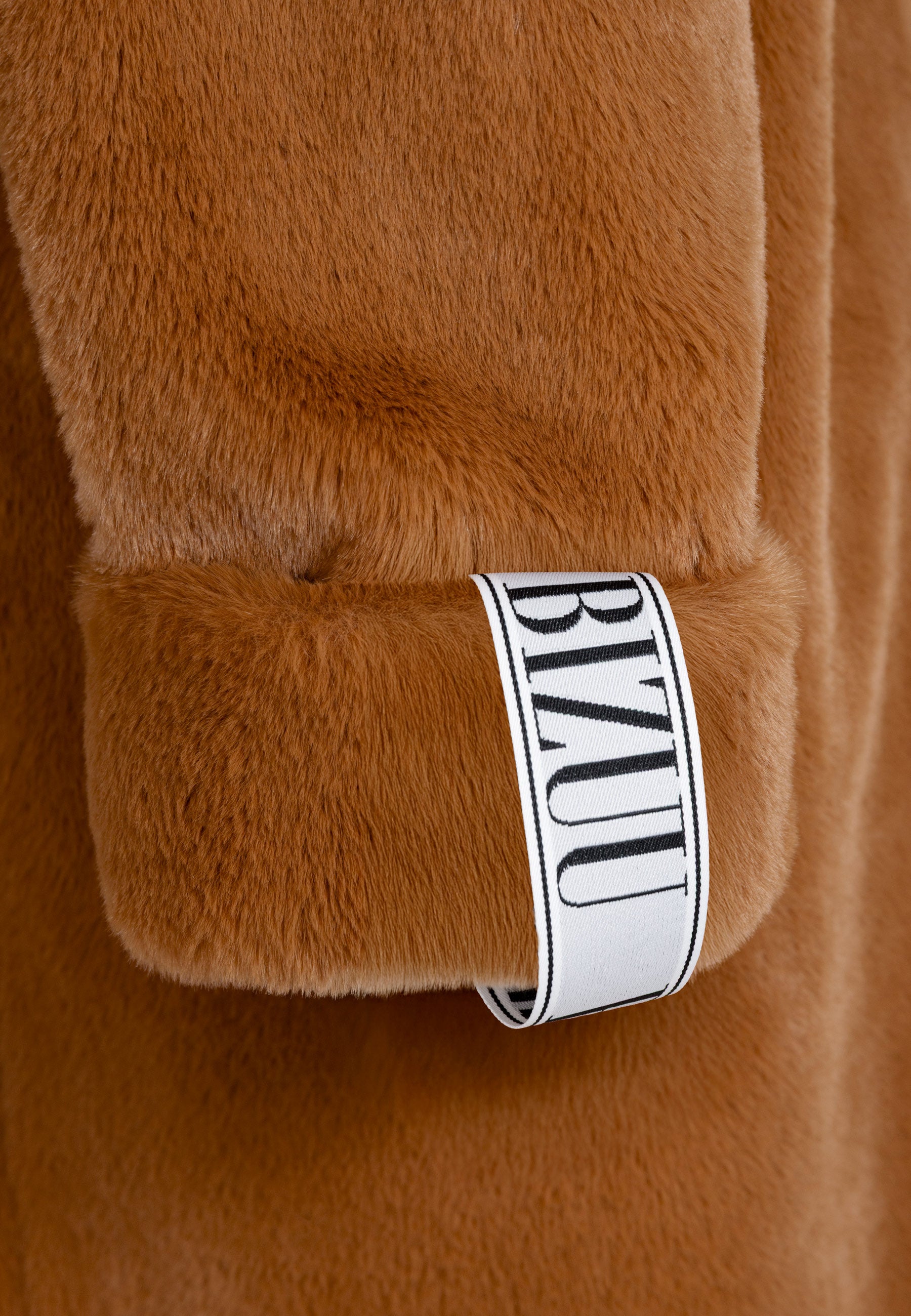 Zbliżenie na logowaną metkę na rękawie rudego futra DOLOMITES.
