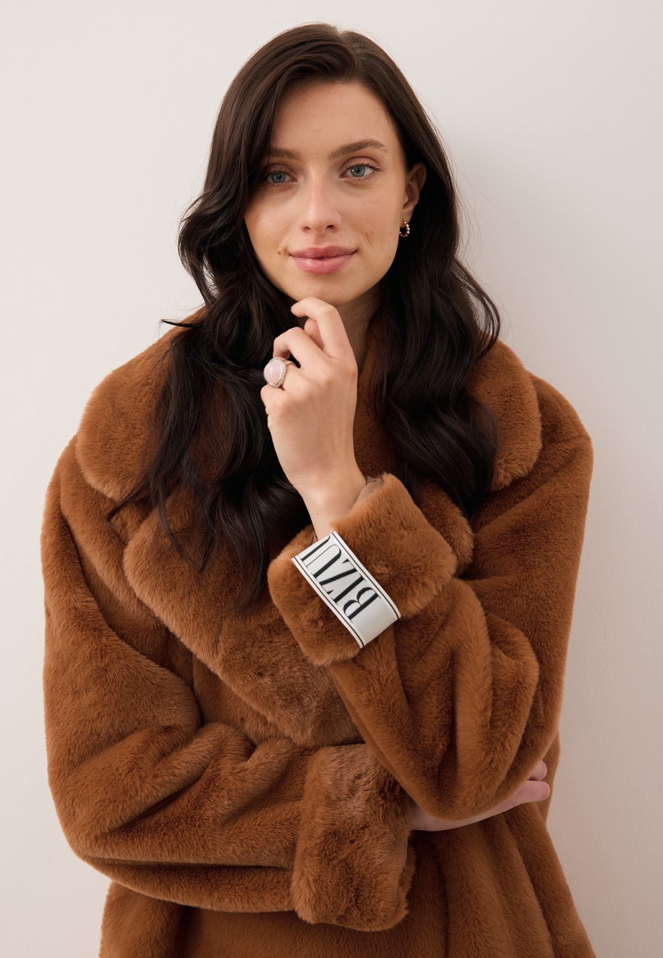 Zbliżenie na modelkę z ręką przy twarzy prezentującą logowaną metkę na rękawie futra DOLOMITES.