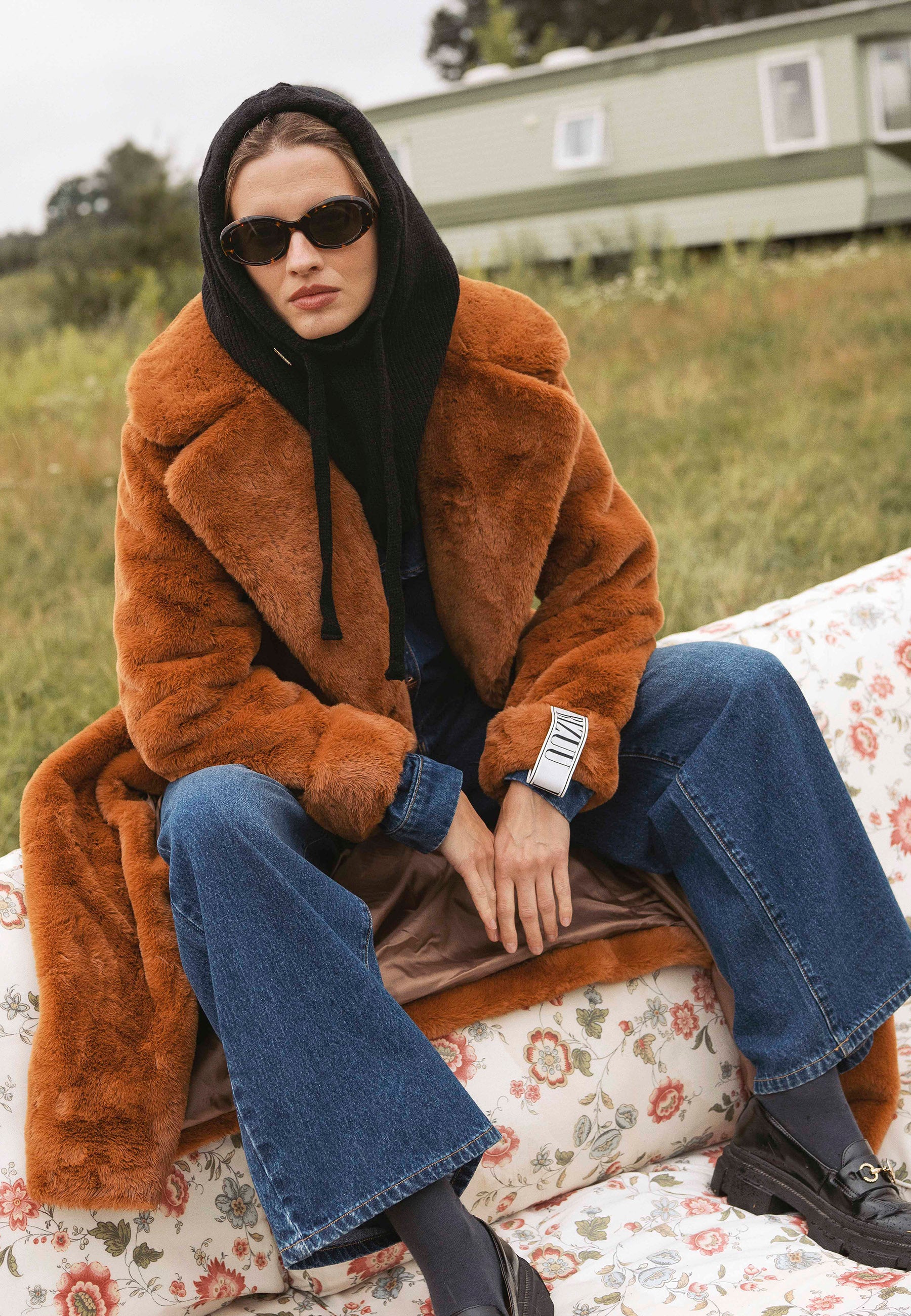 Modelka siedząca na oparciu kanapy w rudym płaszczu DOLOMITES.