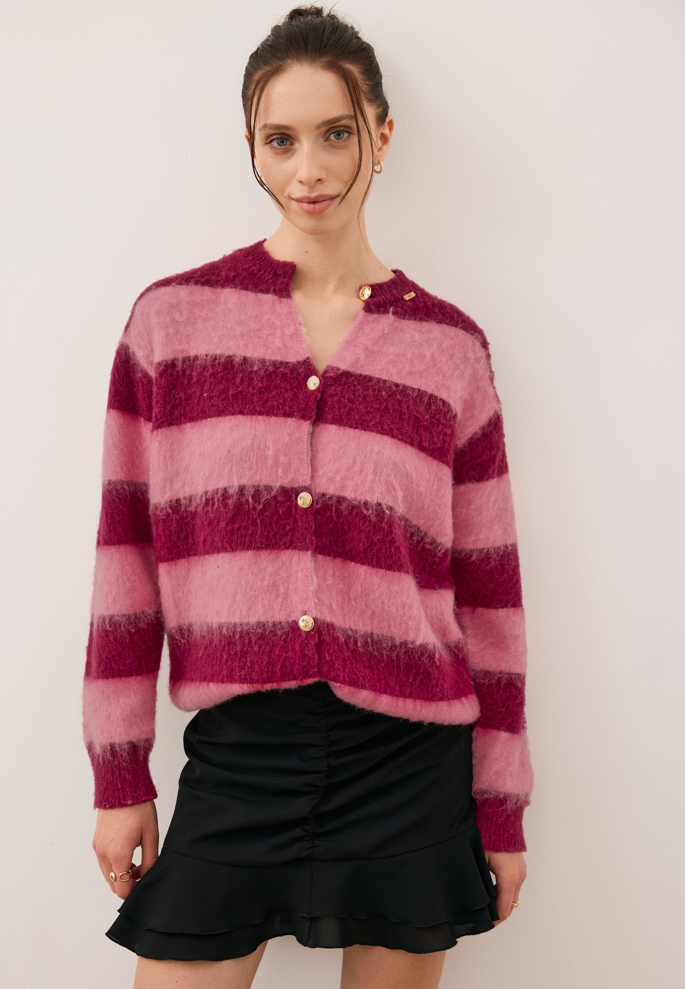 Modelka w kardiganie w różowo-bordowe paski EZE oraz spódniczce mini ROSALIAN.