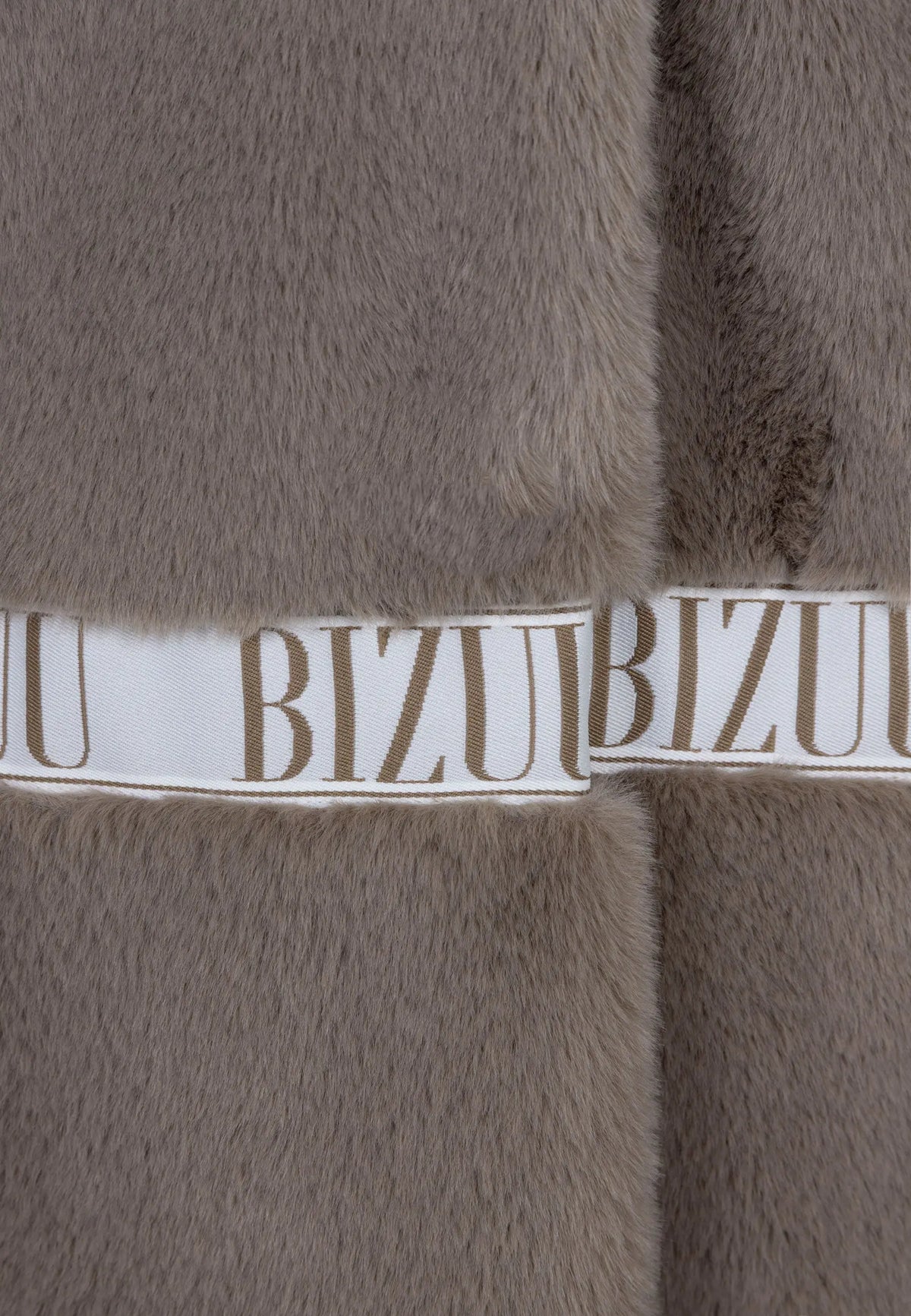 Zbliżenie na logowaną taśmę na futrze FLORENCE taupe.