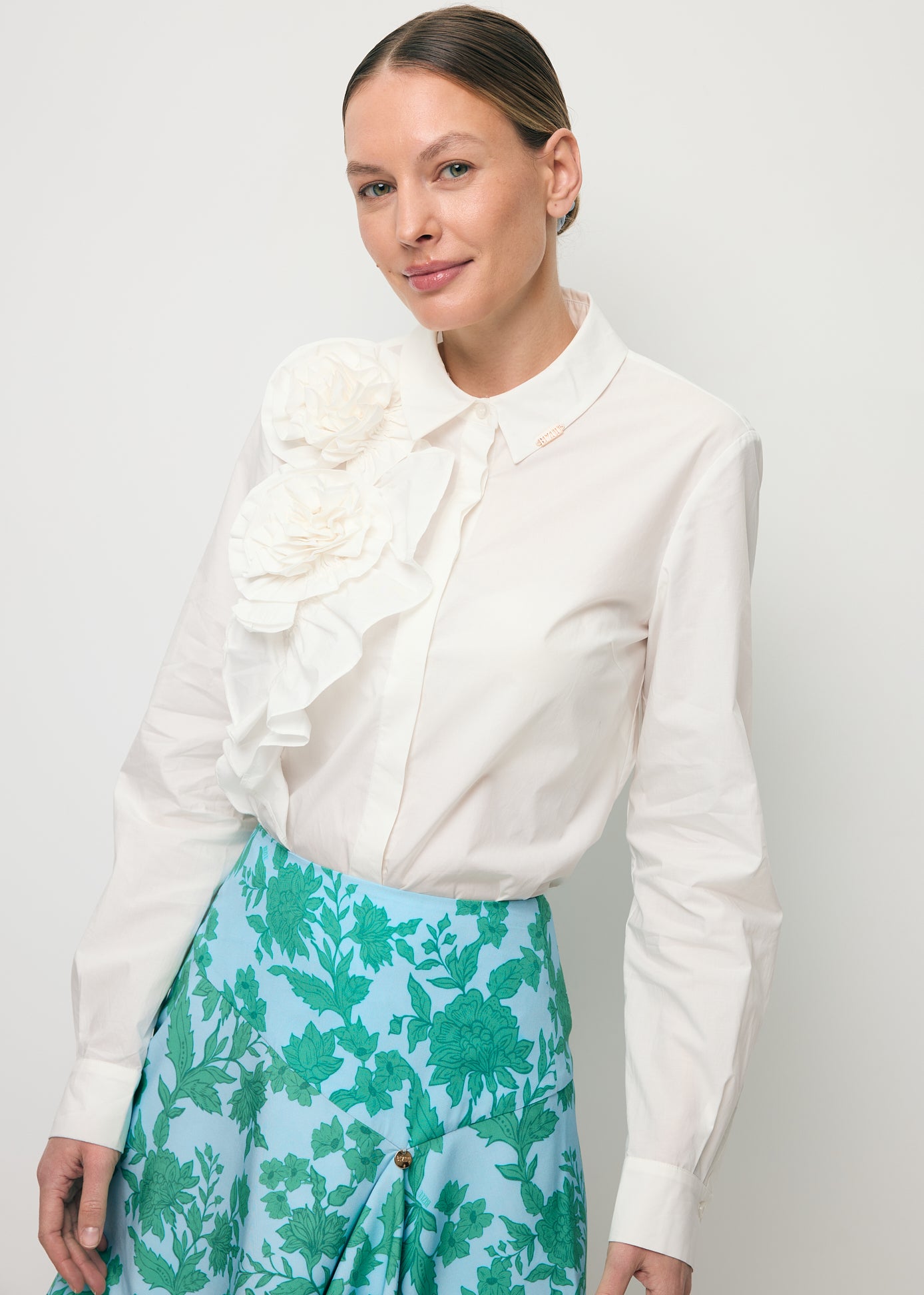 Zbliżenie na modelkę w białej koszuli z ozdobnymi różami FLOWYA.