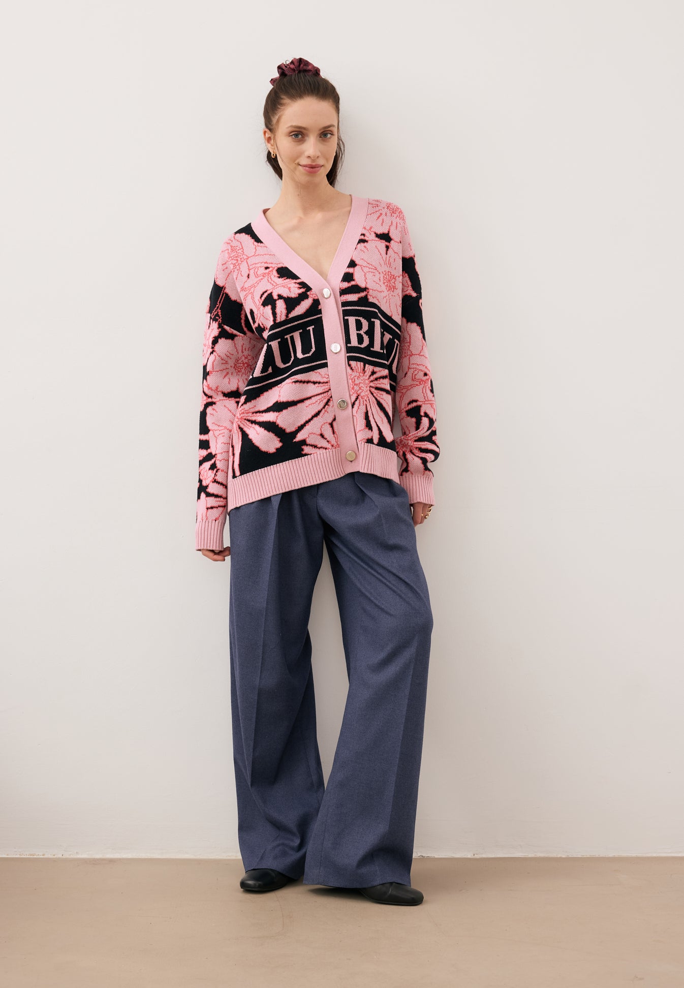 Modelka ubrana w kwiatowy sweter ze złotymi guzikami HYLES oraz granatowe spodnie BANOS z szerokimi nogawkami.