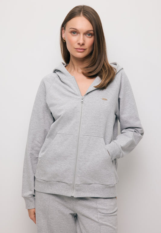 Zbliżenie na modelkę z ręką w kieszeni rozpinanej, szarej bluzy z kapturem IANELLA.