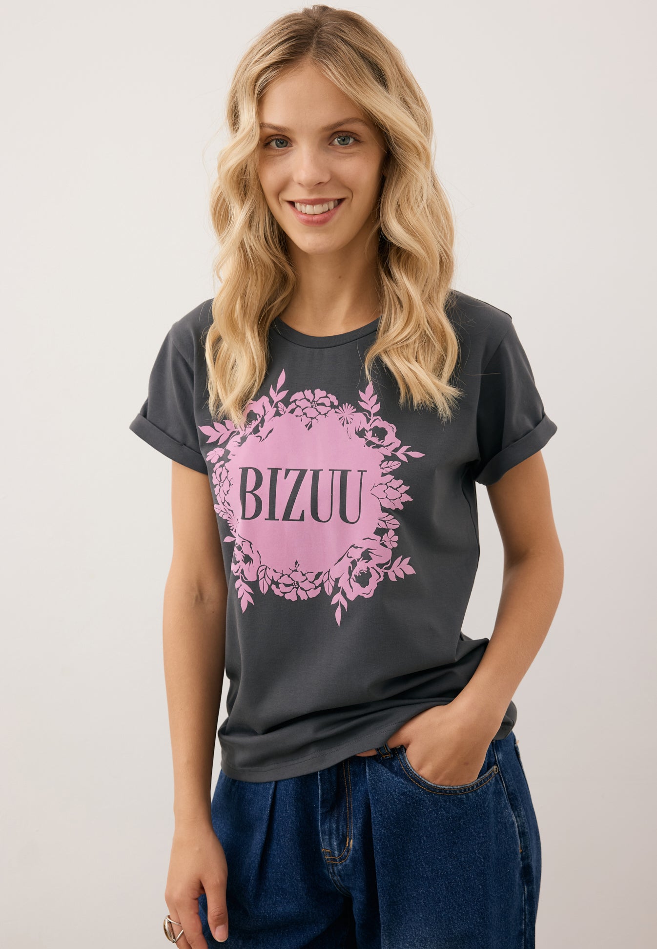 Zbliżenie na modelkę w grafitowym T-shircie IOLA z różową grafiką na przodzie.