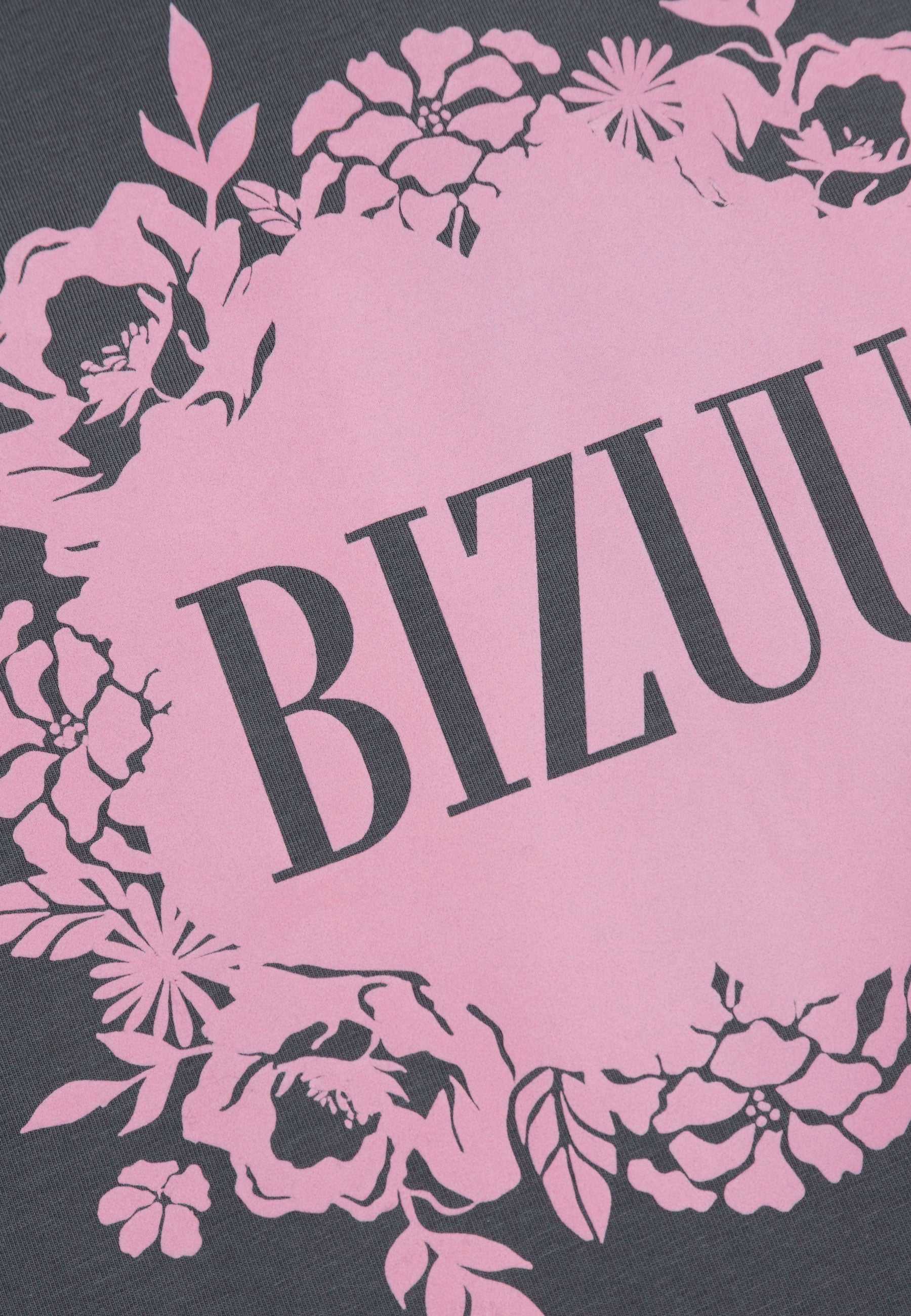 Zbliżenie na różową aplikację z logo Bizuu na grafitowym T-shircie IOLA.