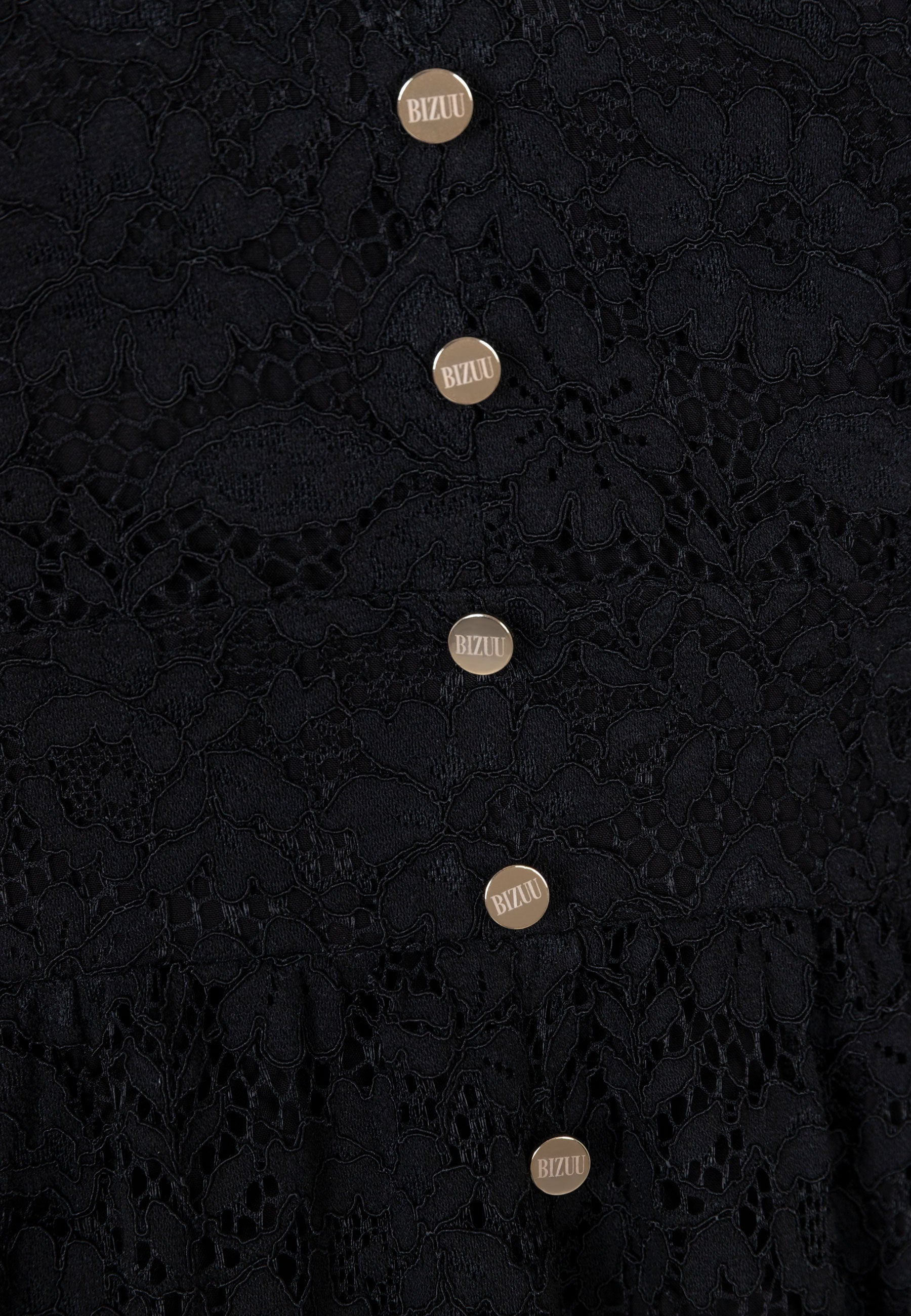 Zbliżenie na złote guziki z przodu koronkowej sukienki ISORELLA.